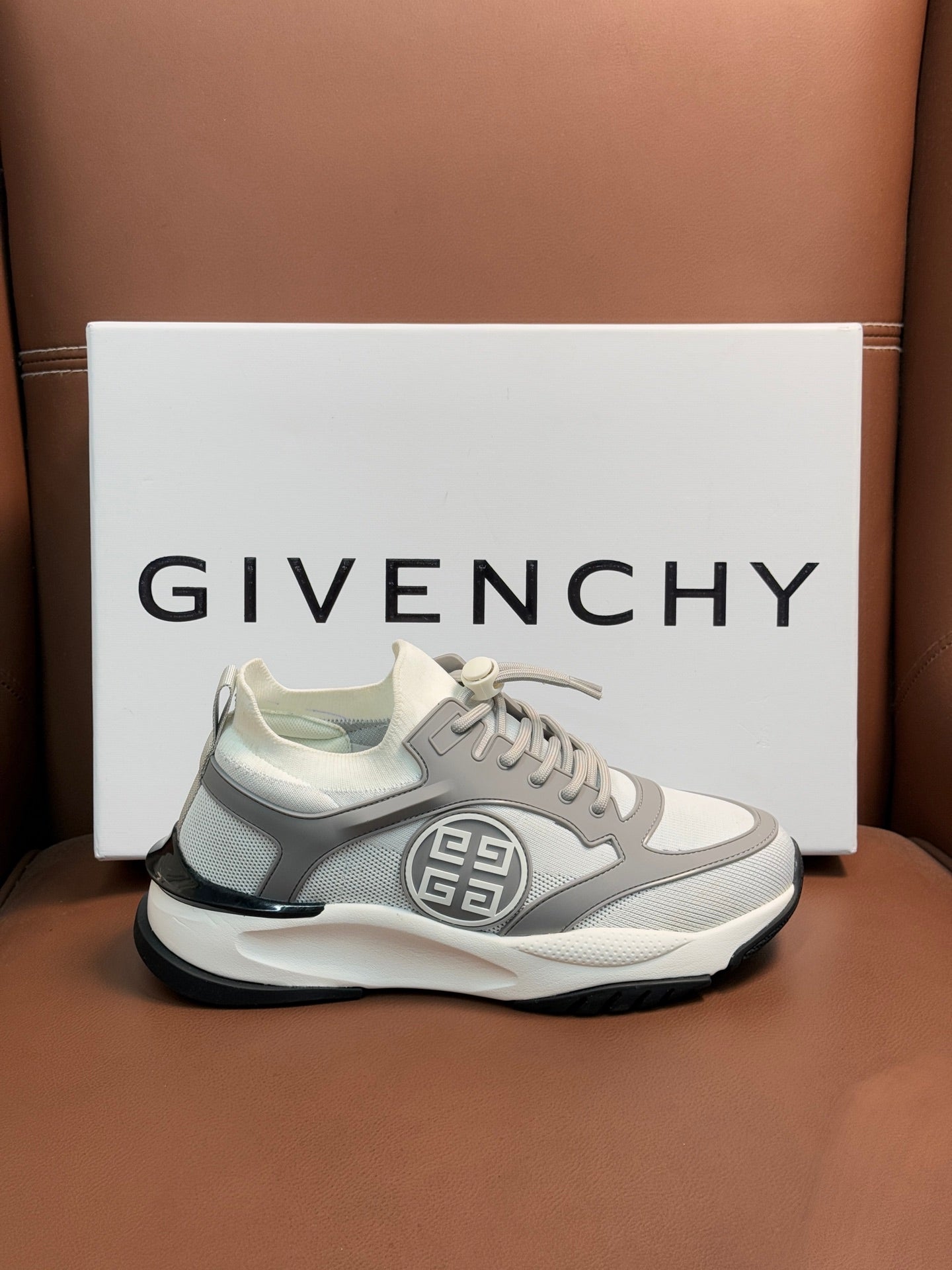 Light gray chunky sneakers with lace-up front and oval side logo patch.