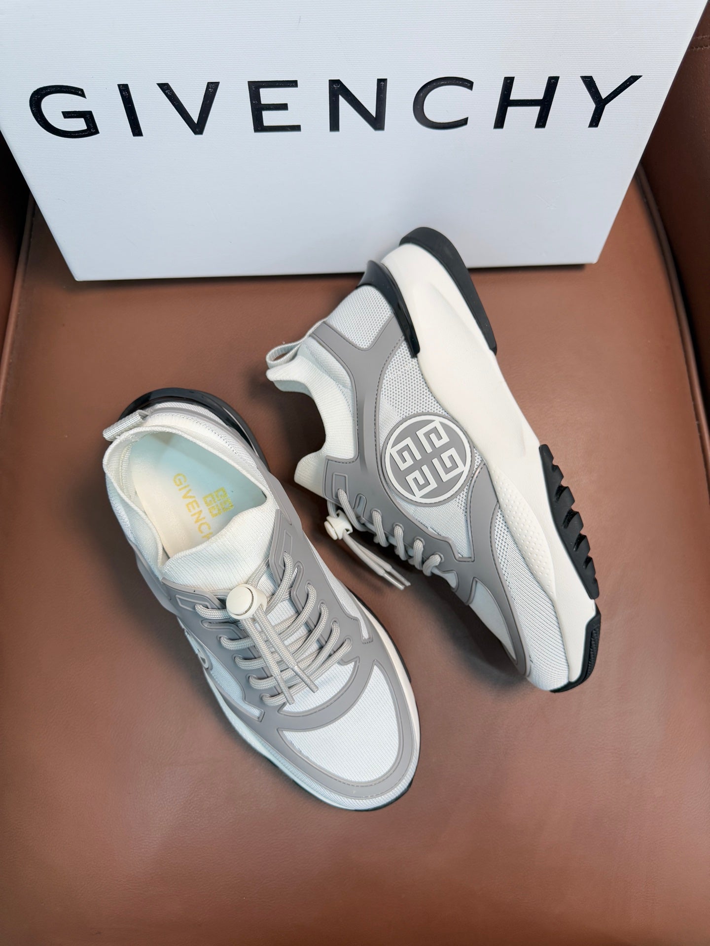 Light gray lace-up sneakers with black heel tab and circular side logo.