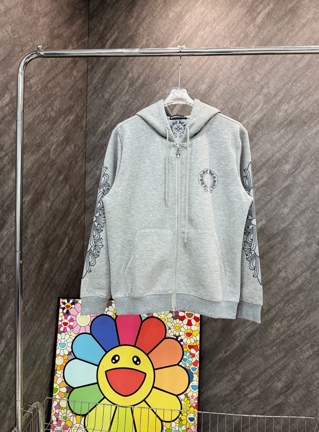 Grey zip-up hoodie with hood and small chest graphic, long sleeves