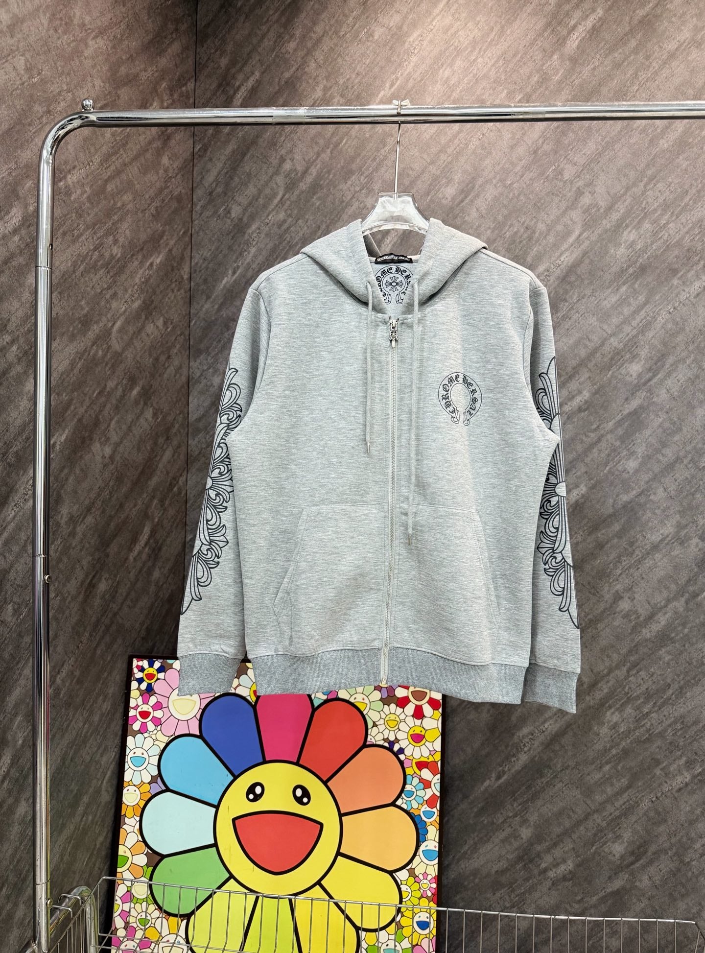 Grey zip-up hoodie with hood and small chest graphic, long sleeves