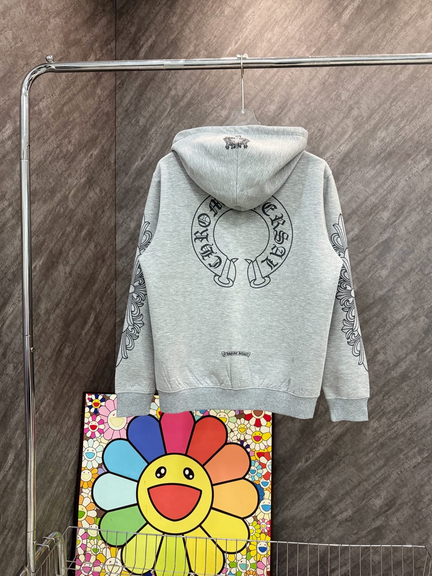 Grey zip-up hoodie with hood and circular graphic on chest, long sleeves