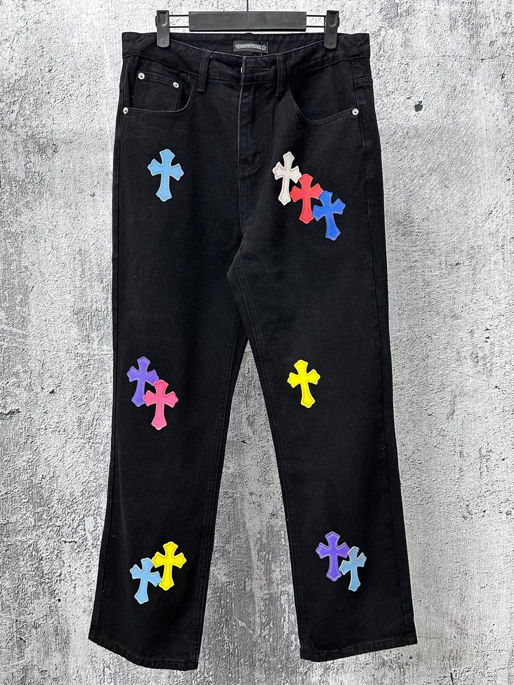 Black denim pants with colorful cross patches, front pockets and straight leg