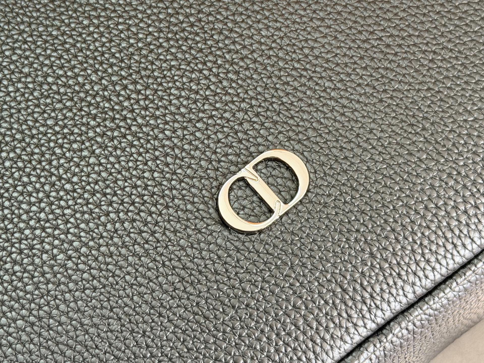 Dior men’s bag leather close-up with gold-tone D logo emblem