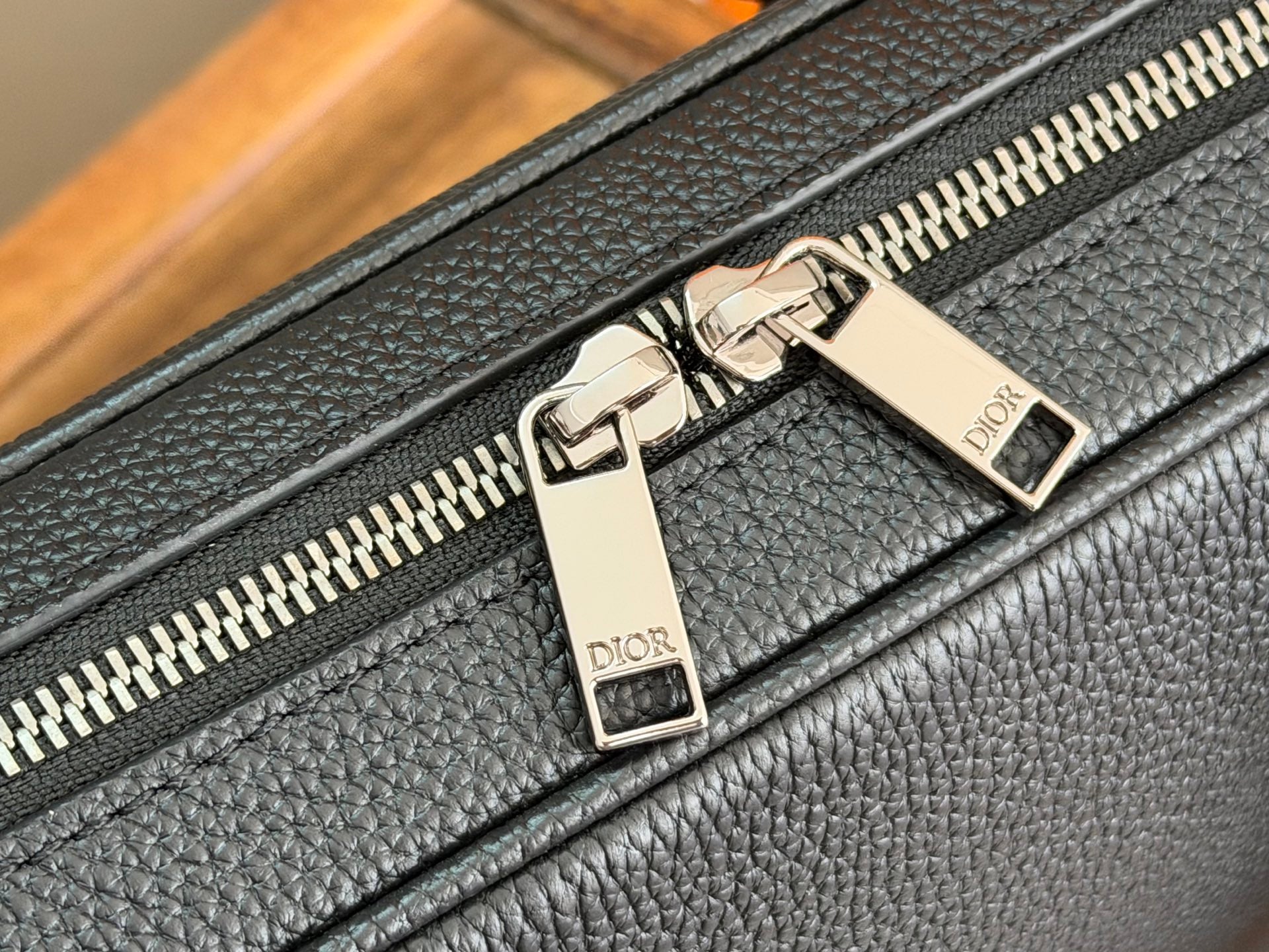 Dior men’s bag zipper pull close-up with gold-tone Dior branding