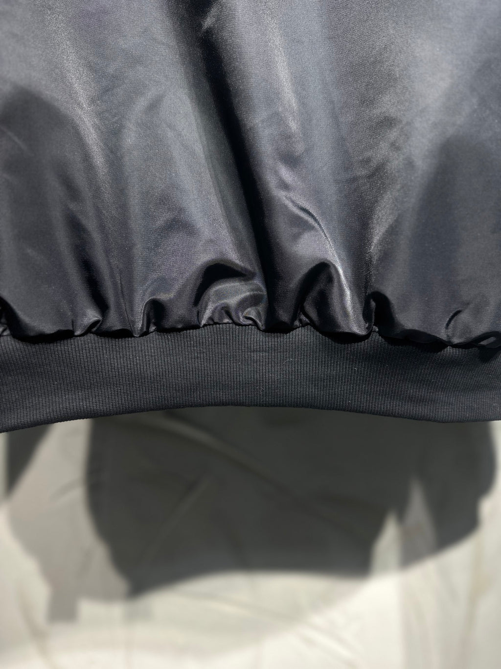 Long hooded jacket hem close-up, dark gray with ribbed knit band