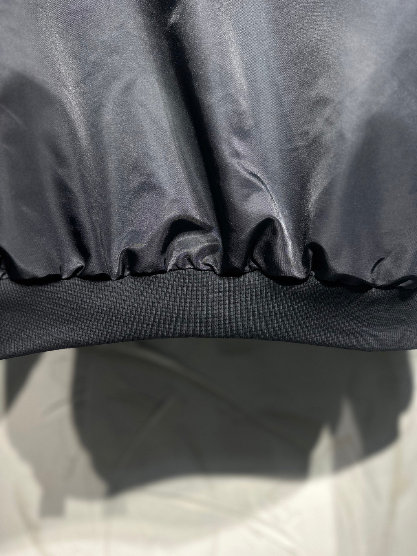 Long hooded jacket hem close-up, dark gray with ribbed knit band