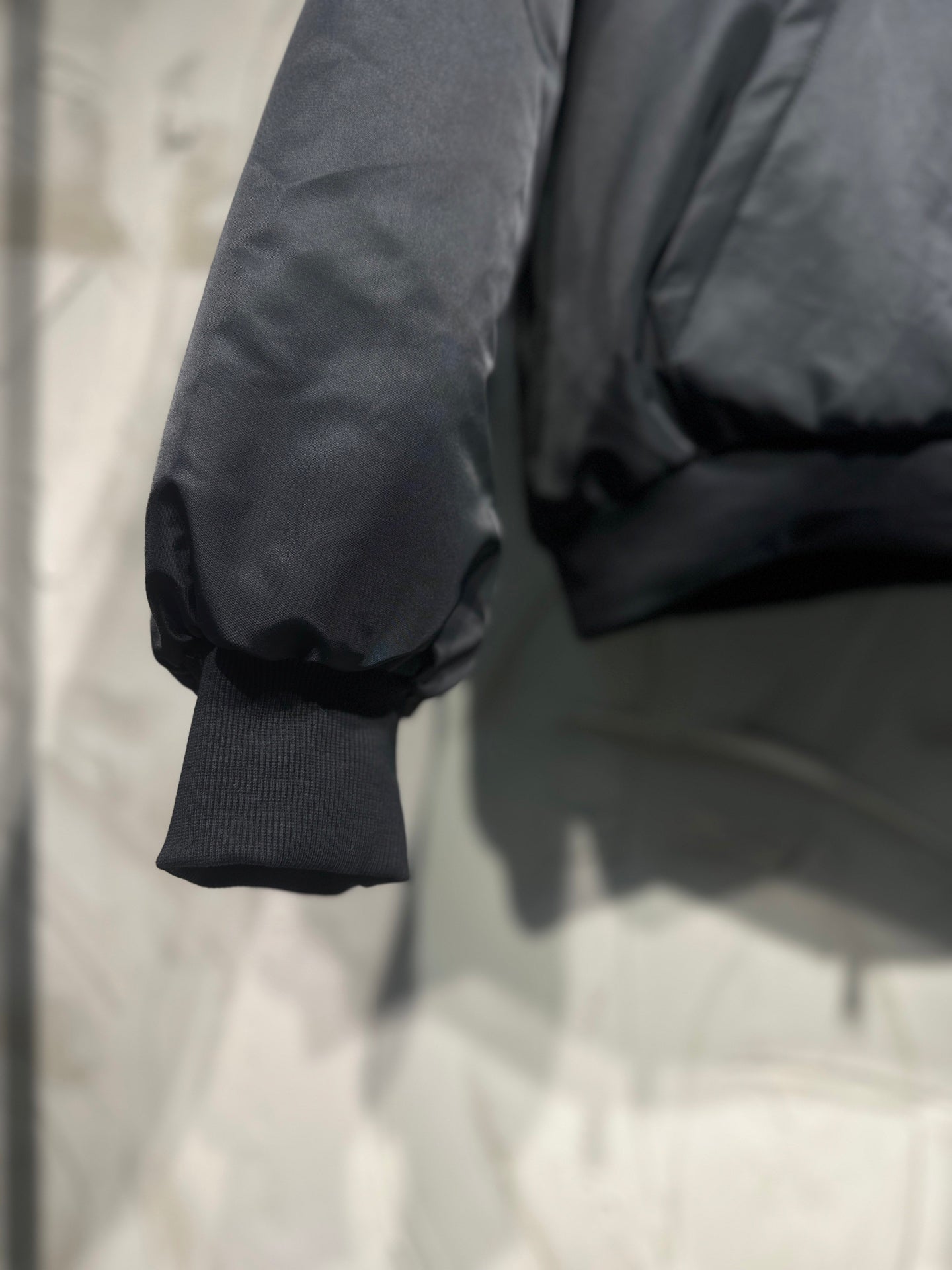 Long hooded jacket sleeve close-up, dark gray puffed shoulder and rib cuff