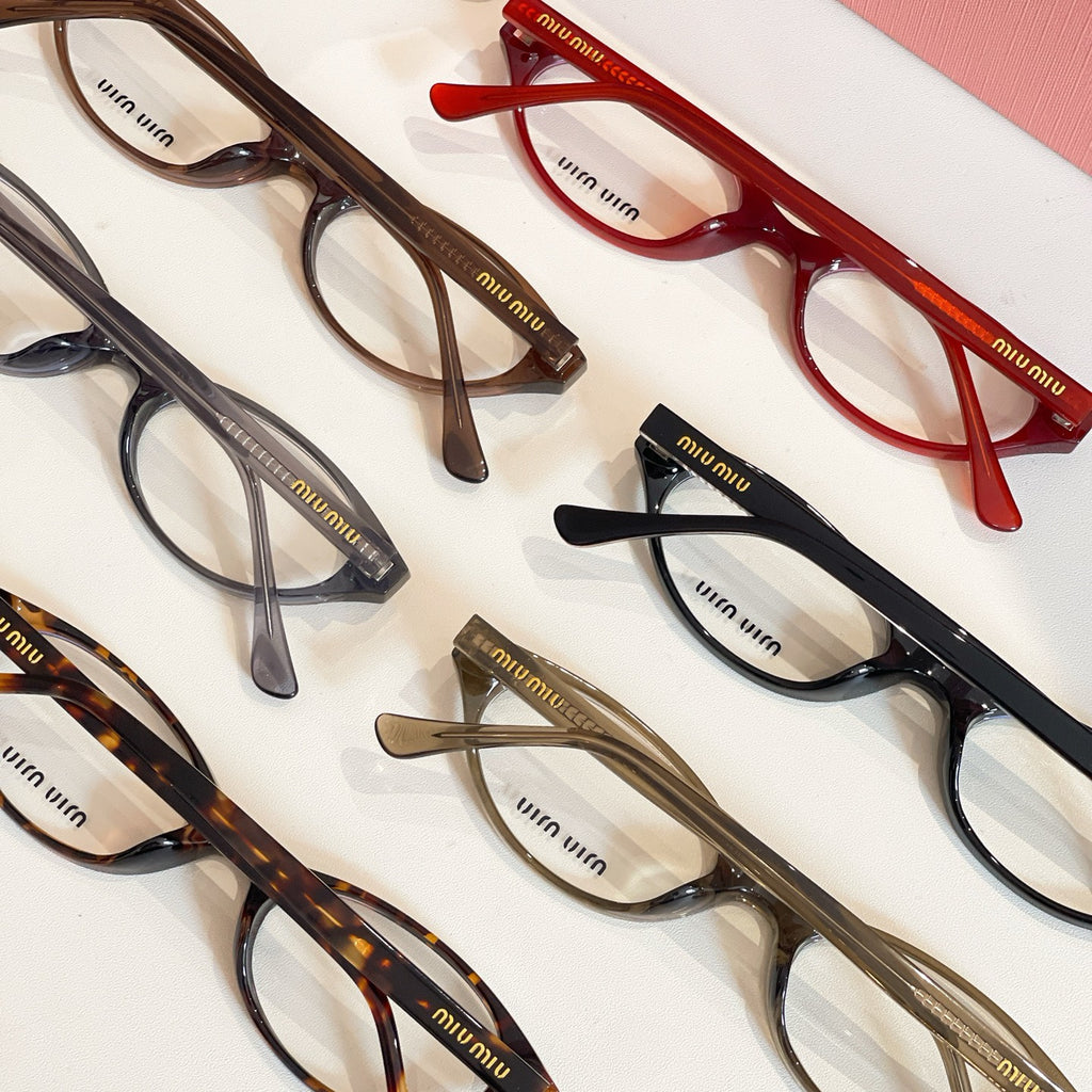 Assorted Miu Miu eyeglasses with dark, red, and tortoise frames arranged together