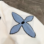 White knit sweater with blue flower applique and black center, crew neck