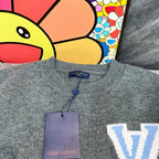 Gray knit long-sleeve top with small button placket and Louis Vuitton-branded neck label