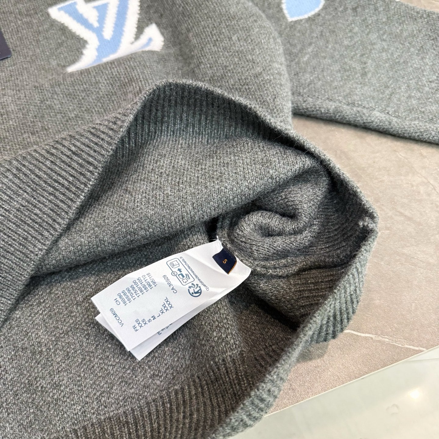 Gray knit long-sleeve sweater cuff and folded fabric detail with tag