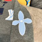 Gray knit long-sleeve sweater with large blue flower-like graphic and LV emblem background