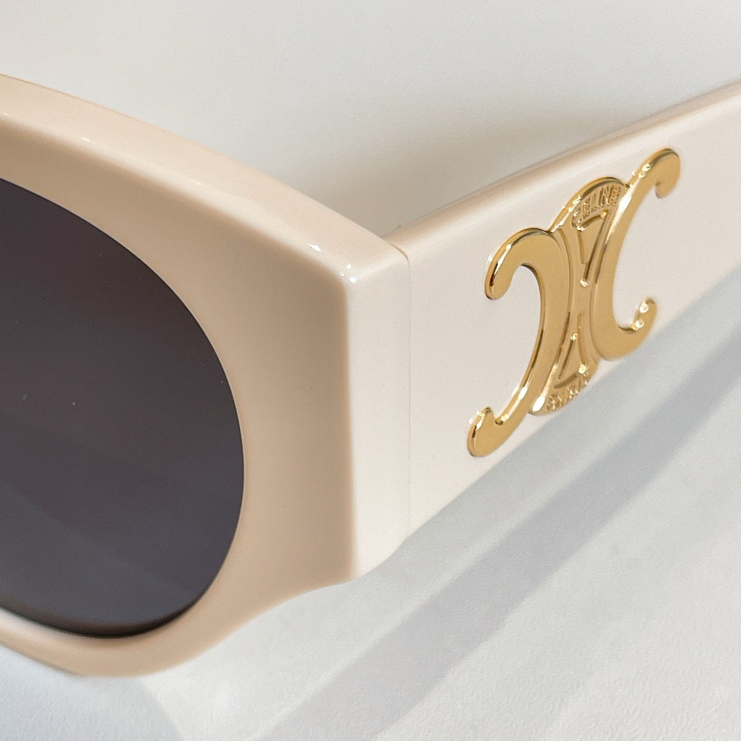 Celine sunglasses close-up: gold emblem on cream frame temple