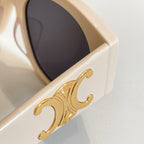 Celine sunglasses close-up: gold emblem on cream frame with dark lens