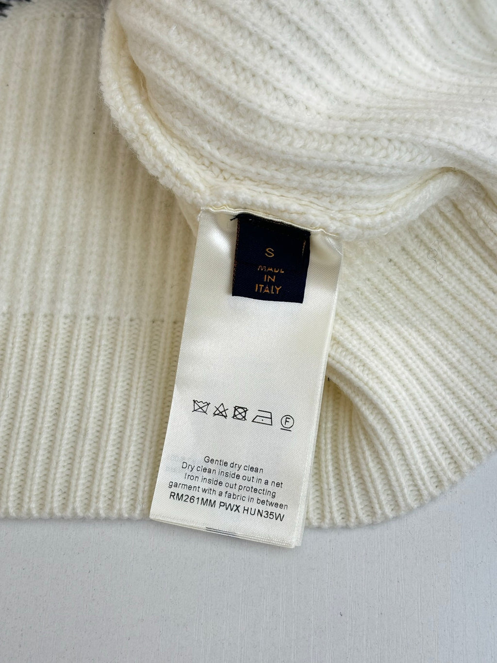 Cream knit sweater with long sleeves, collar tag and care label