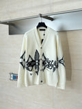 Ivory knit cardigan with black star-like graphic and button front
