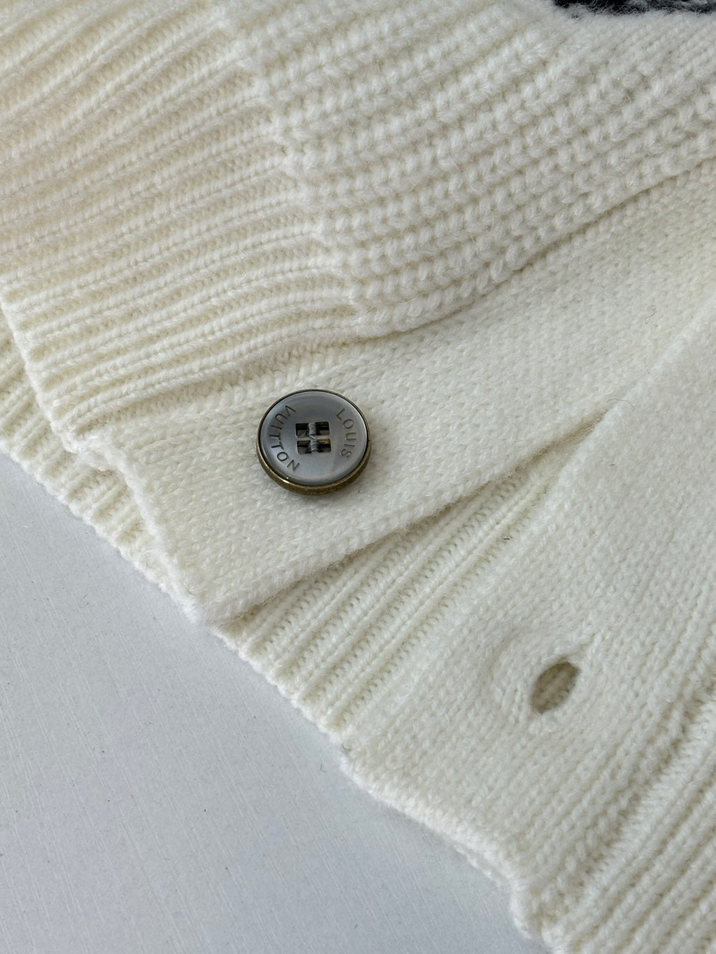 Ivory knit cardigan fabric close-up with round gray buttons