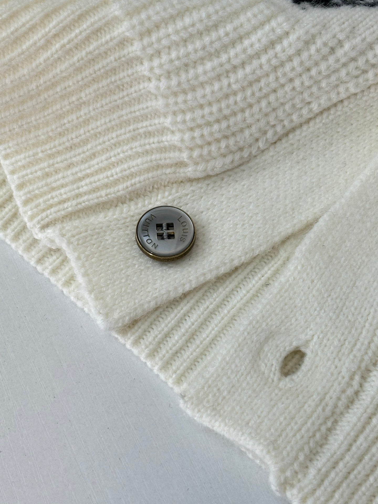Ivory knit cardigan fabric close-up with round gray buttons