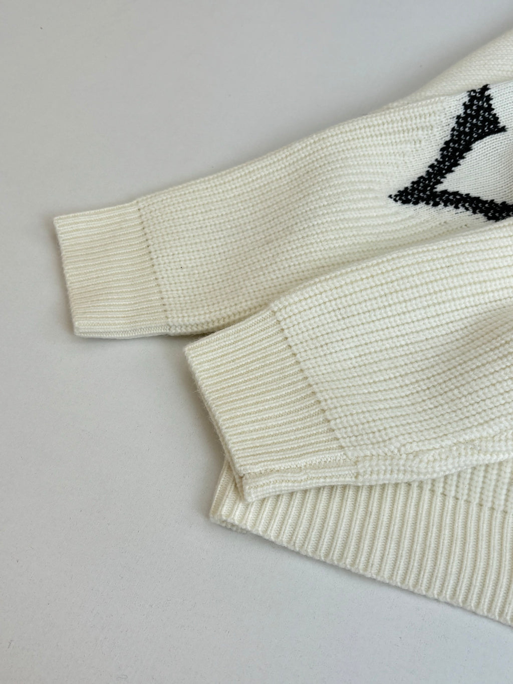 Ivory knit cardigan sleeve and hem detail with black graphic motif