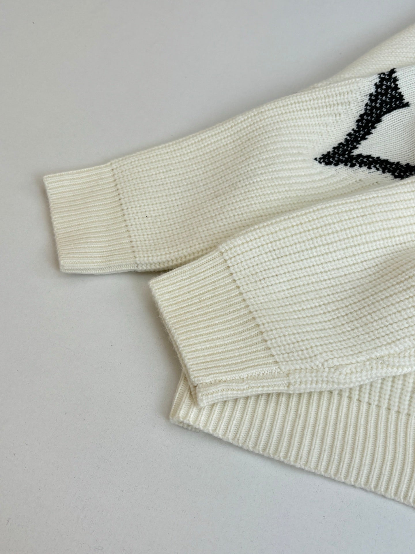 Ivory knit cardigan sleeve and hem detail with black graphic motif
