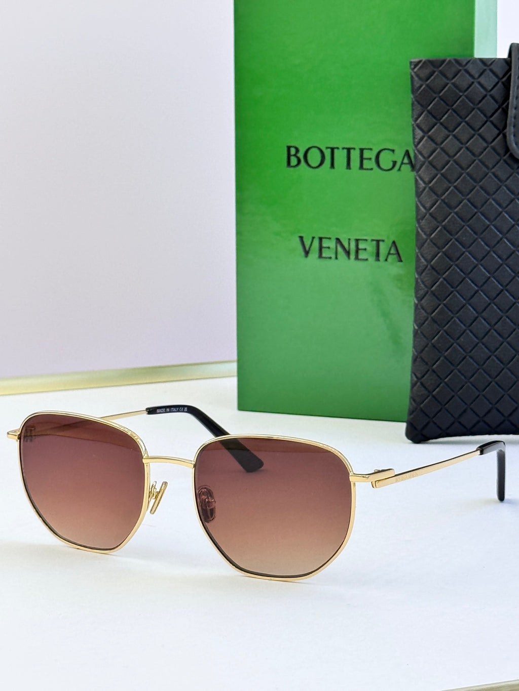 Gold-frame sunglasses with burgundy lenses and black temple detail