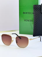 Gold-frame sunglasses with burgundy lenses and black temple detail