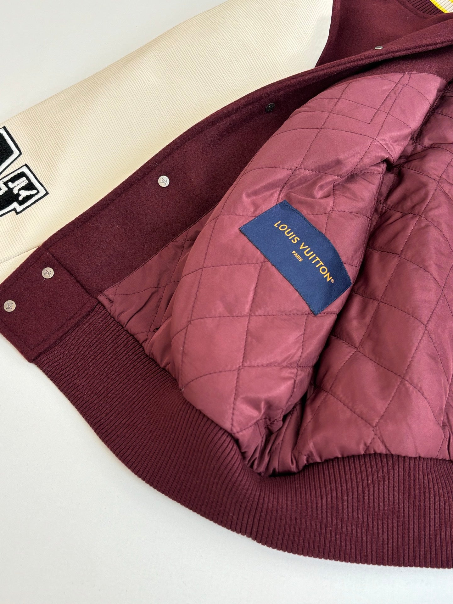 Burgundy quilted hood on maroon long garment with Louis Vuitton logo patch