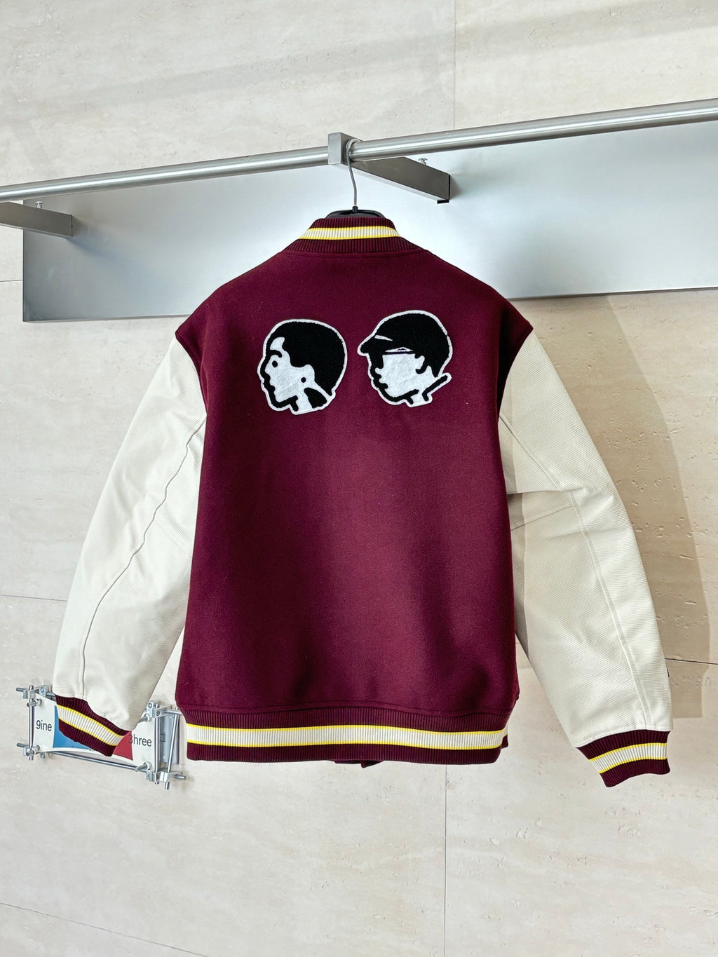 Varsity jacket, maroon back with two dog-head patches, striped hem, button front.