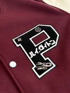 Maroon varsity jacket front patch detail with black-and-white graphic and button.