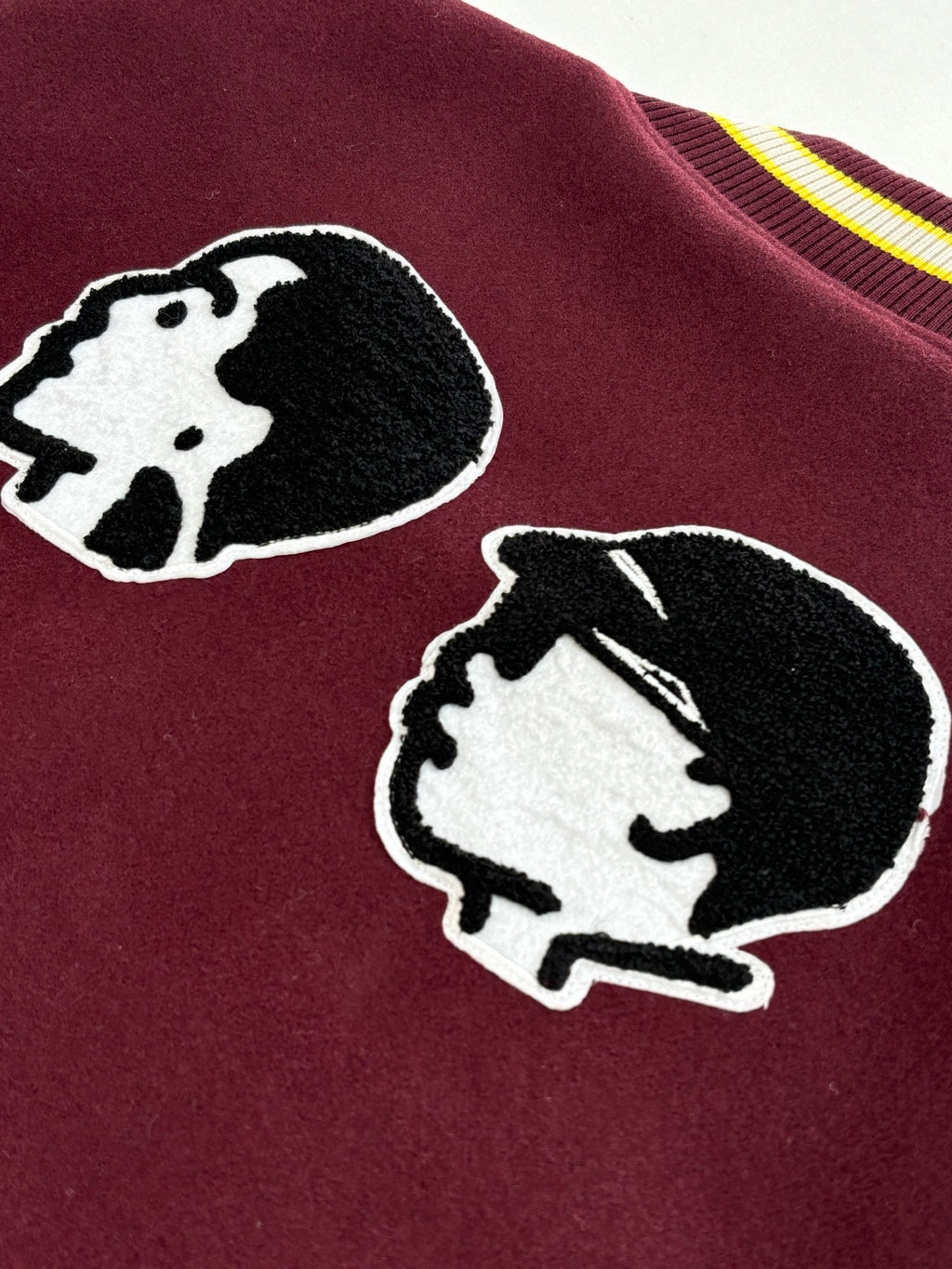 Maroon varsity jacket close-up showing two dog-head applique patches.