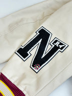 White varsity sleeve with black letter patch and maroon-and-striped ribbed cuff.