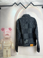 Back view of dark denim jacket with monogram print and yellow button detail.