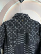 Dark denim jacket back close-up with monogram print and curved yoke seam.