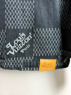 Denim jacket cuff close-up with "Louis Vuitton" patch and stamped monogram pattern.