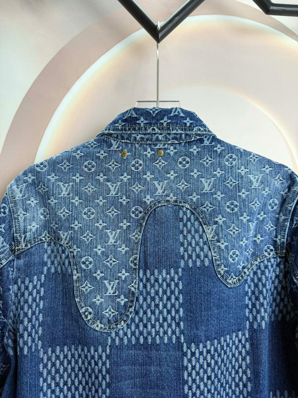 Blue denim jacket back close-up with curved yoke seam and stitched patch panel