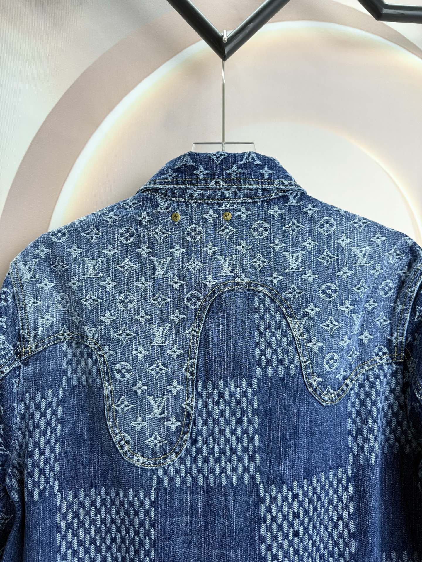 Blue denim jacket back close-up with curved yoke seam and stitched patch panel