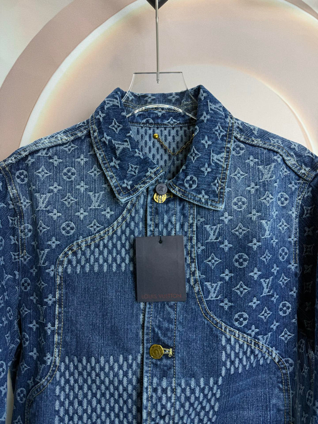 Blue denim jacket close-up showing collar, button placket, and logo pattern