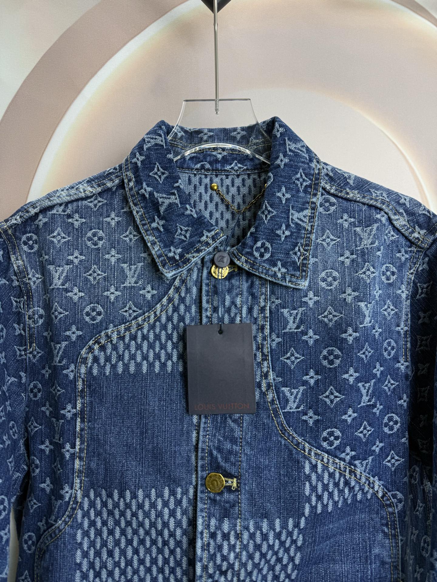 Blue denim jacket close-up showing collar, button placket, and logo pattern