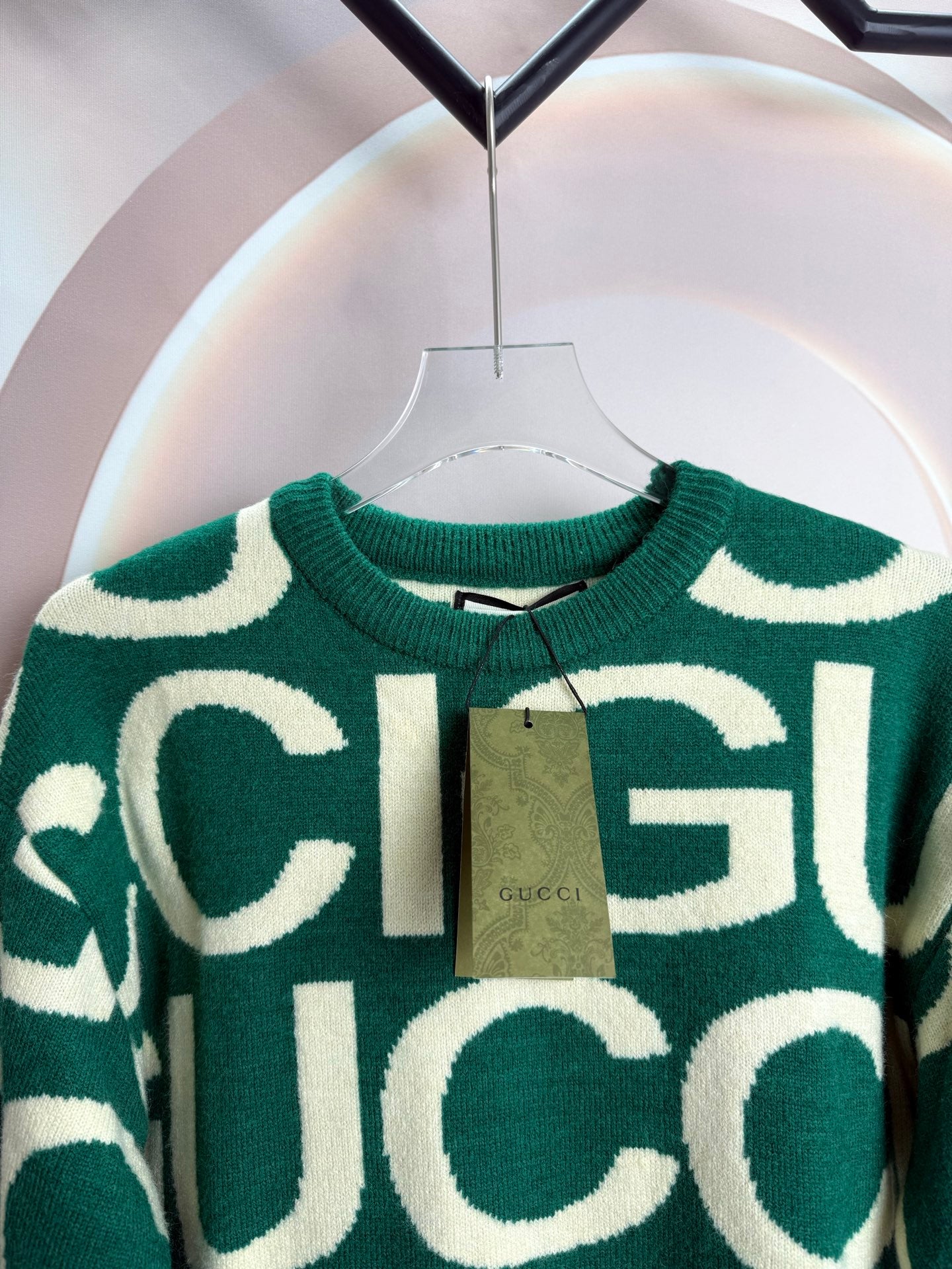 Crewneck knit sweater with green-and-cream logo lettering, close-up