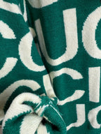 Knit sweater close-up, green fabric with cream lettering pattern