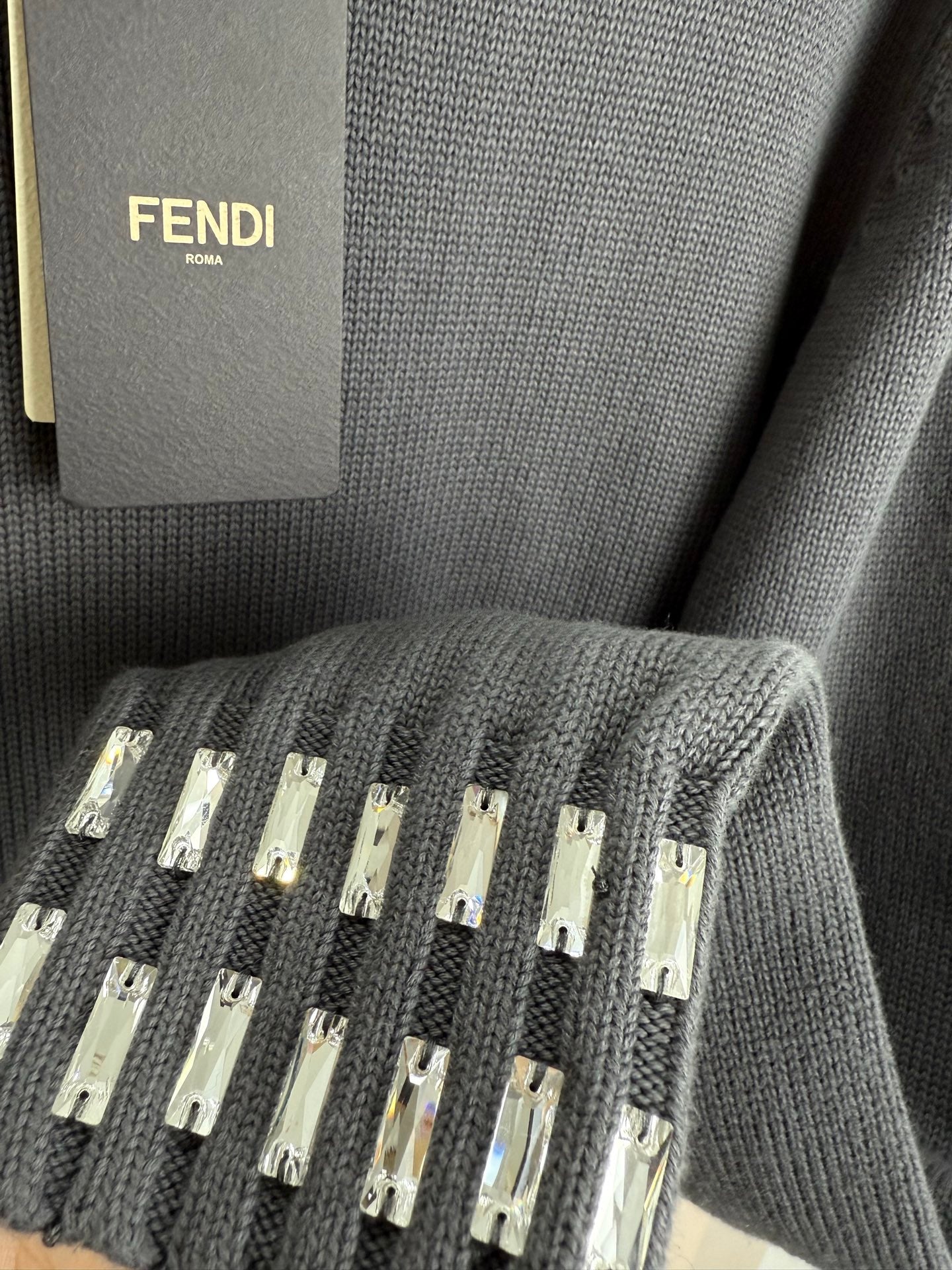 Dark gray knit sweater detail with studded strip embellishment