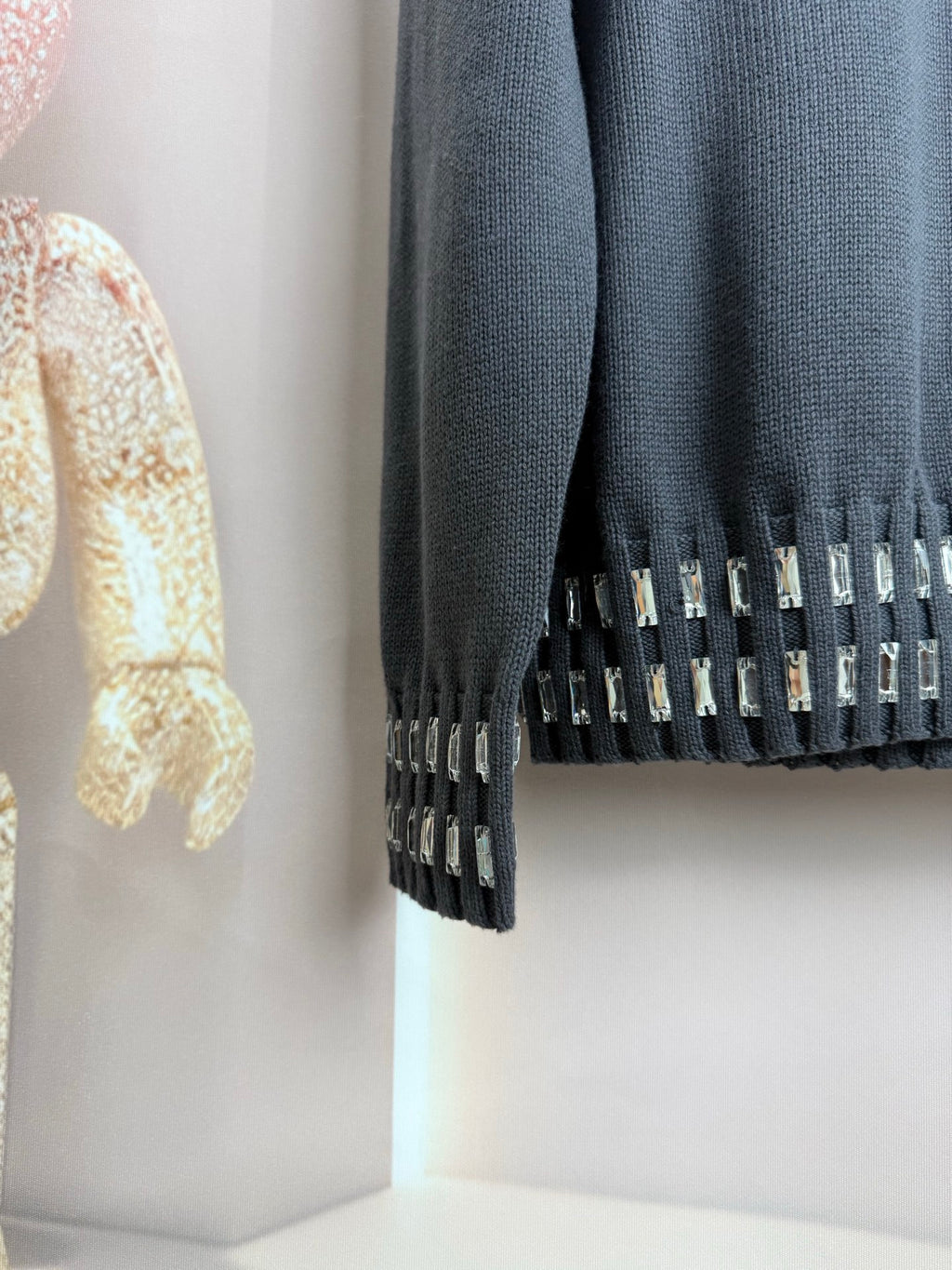 Dark gray sweater cuff with vertical studded trim and ribbed knit