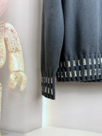 Dark gray sweater cuff with vertical studded trim and ribbed knit