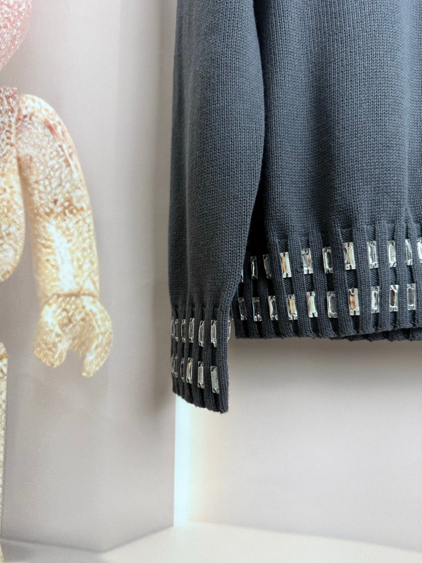 Dark gray sweater cuff with vertical studded trim and ribbed knit