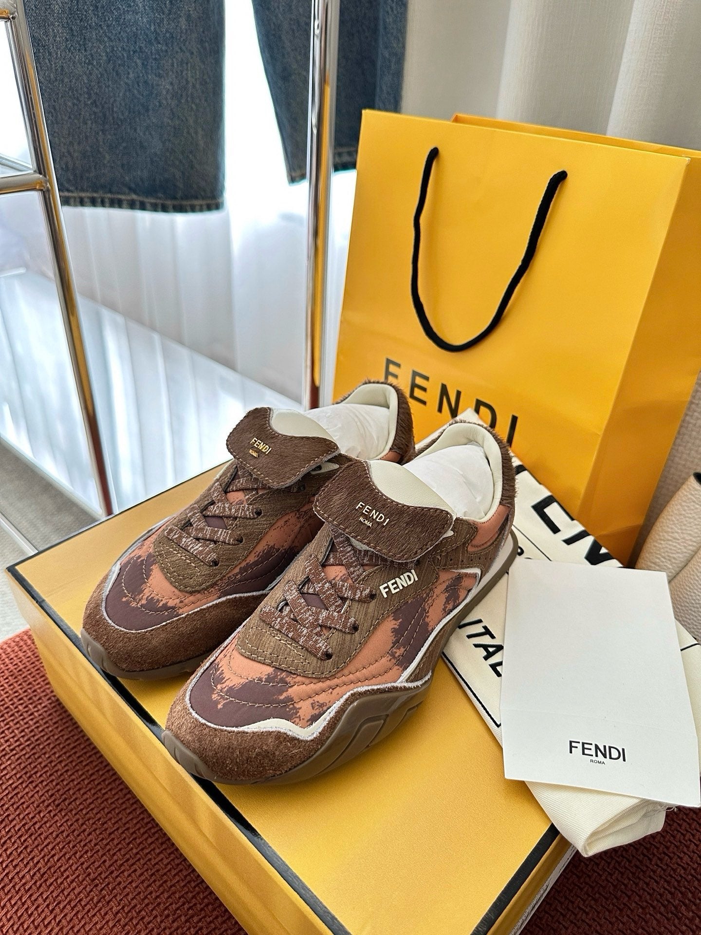 Brown and pink patterned lace-up sneakers with white sole and FENDI branding on sides.