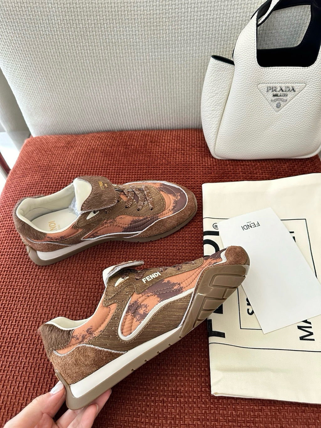 Brown and pink sneakers with white sole and FENDI logo on the heel tab.