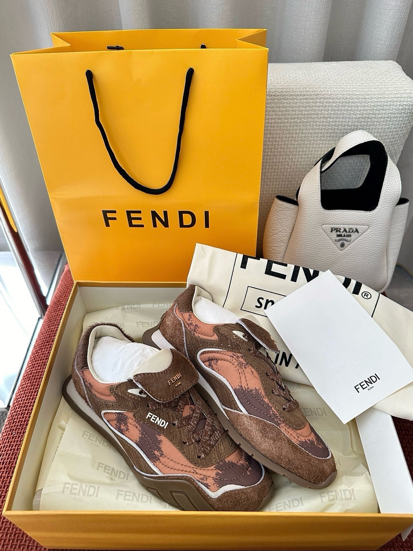 Brown and pink patterned lace-up sneakers with FENDI logos and white rubber sole.