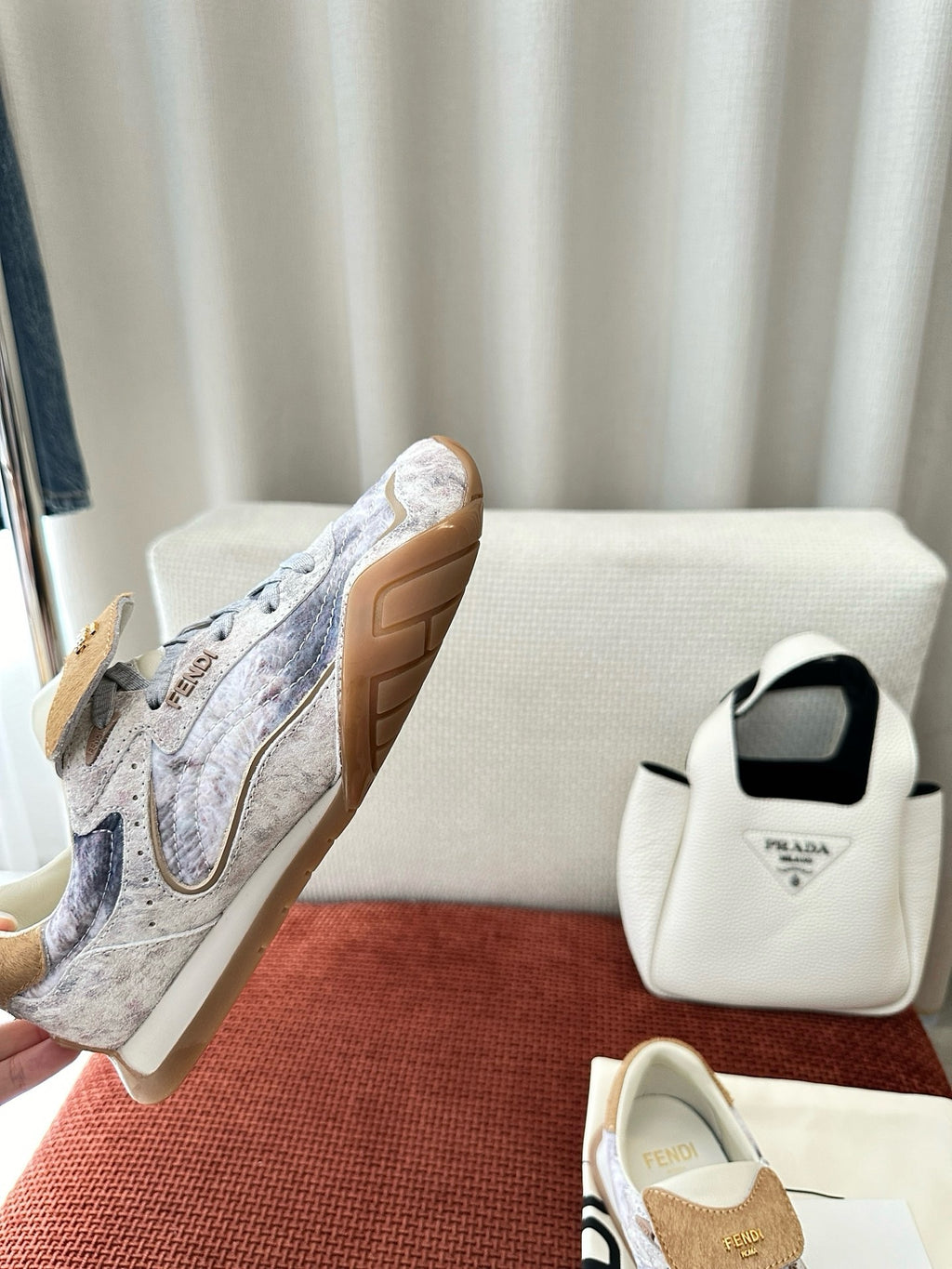 Fendi unisex sneakers shown from side, light blue-gray fabric with tan suede heel patch