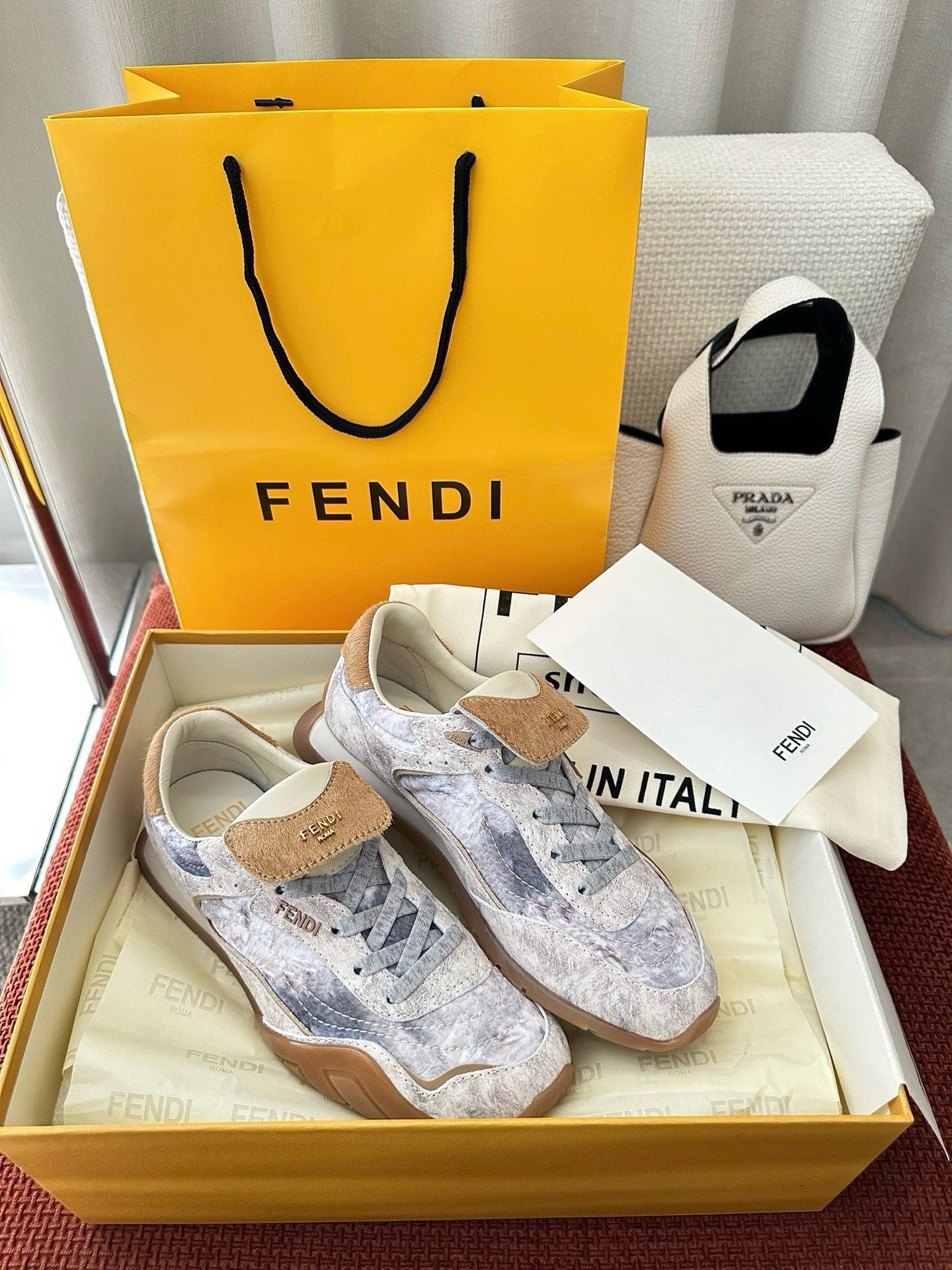 Fendi unisex sneakers with light blue-gray patterned upper and tan suede trim on tongue