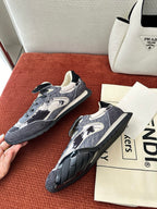 Unisex sneakers two-quarter view: navy-and-white print, lace-up, black tread outsole.